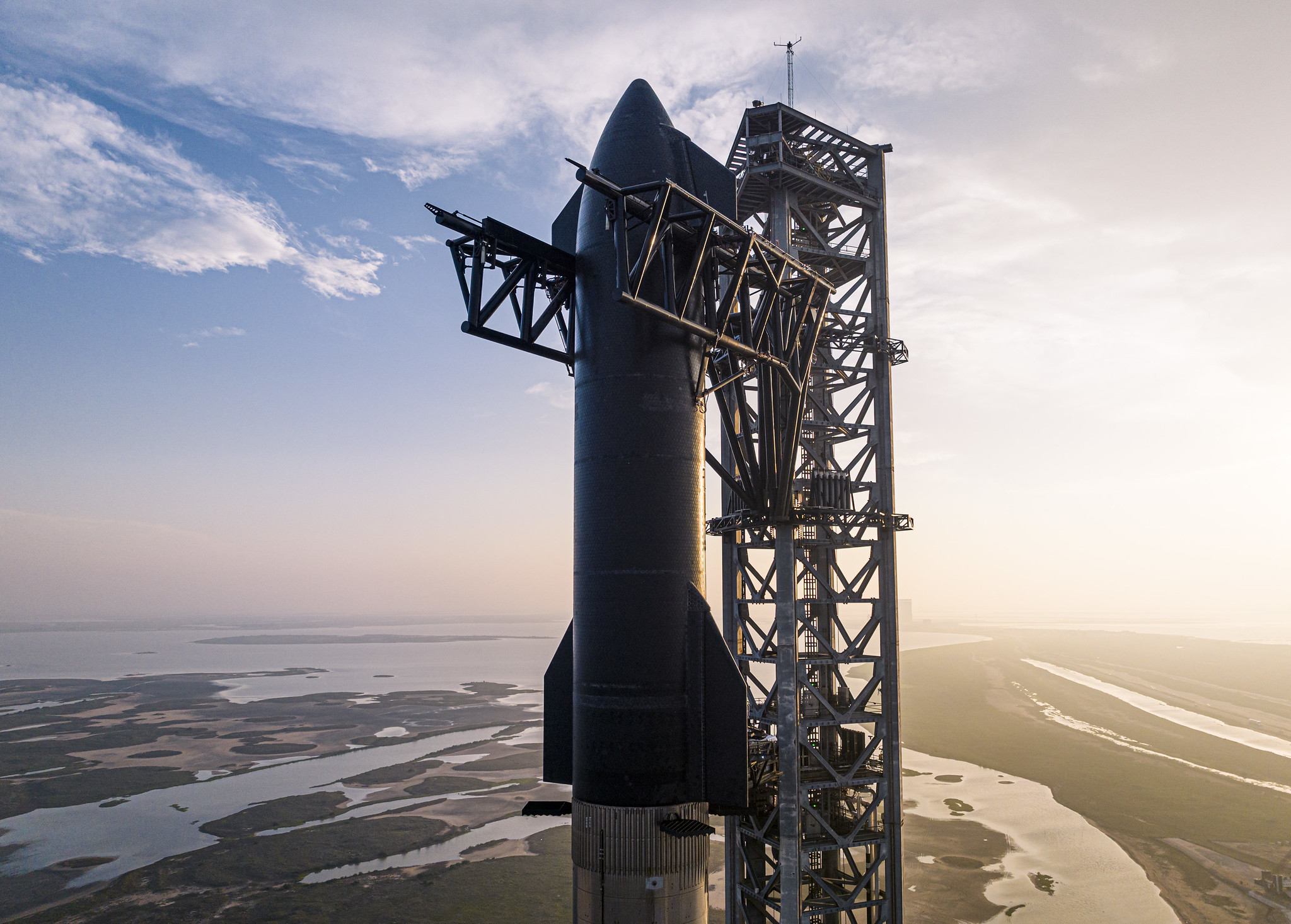 Real SpaceX photograph of Starship beside the launch tower at sunrise